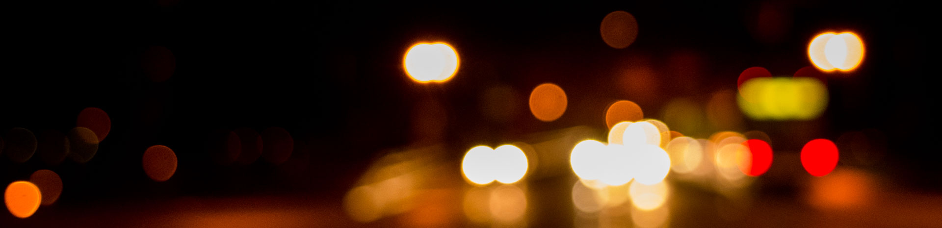 blurry circular lights from automobiles and a street car at night